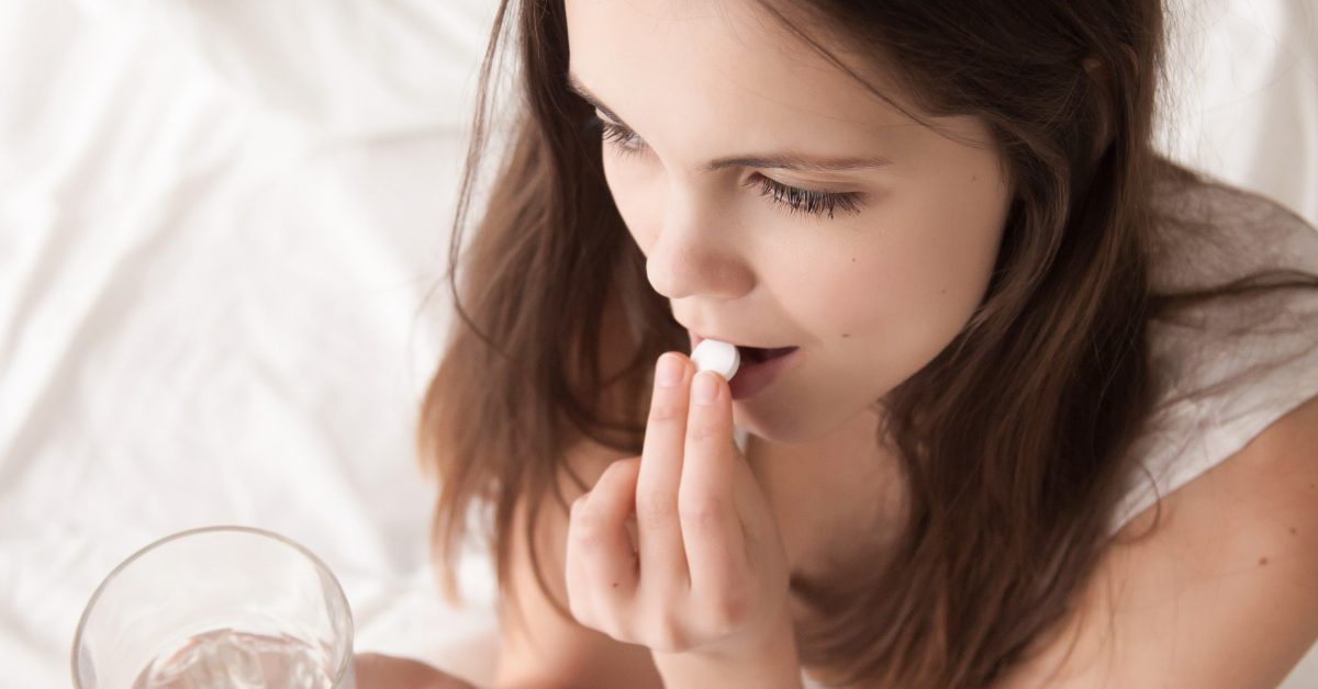 young woman taking a pill